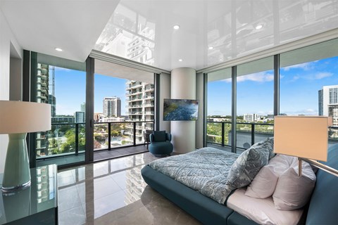 A modern bedroom with a large bed and a view of the city.
