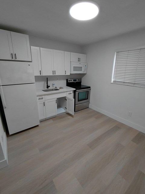 A kitchen with white cabinets and a wooden floor.