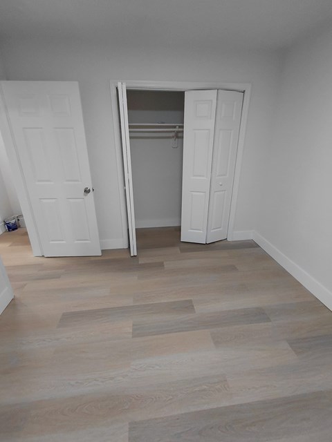 A room with a white door and a white closet with a white interior.