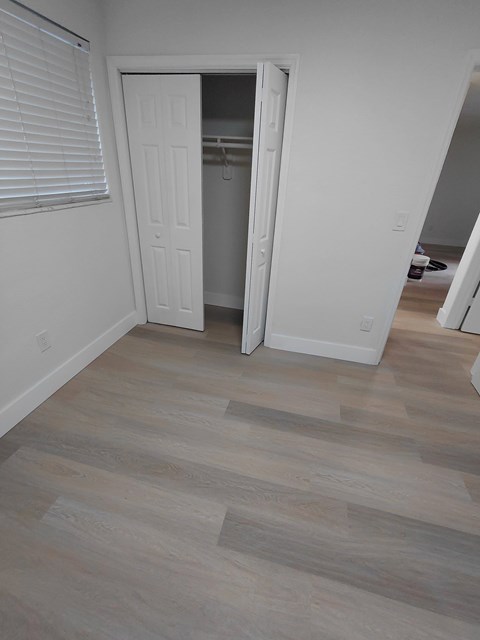 A room with a white door and a wooden floor.