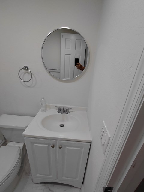 A bathroom with a white toilet, sink and cabinet.