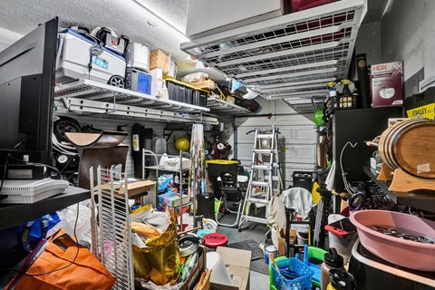 A cluttered garage with various items on shelves and the floor.