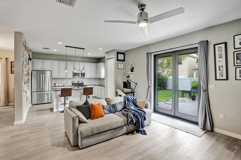 A modern living room with a grey couch and a ceiling fan.