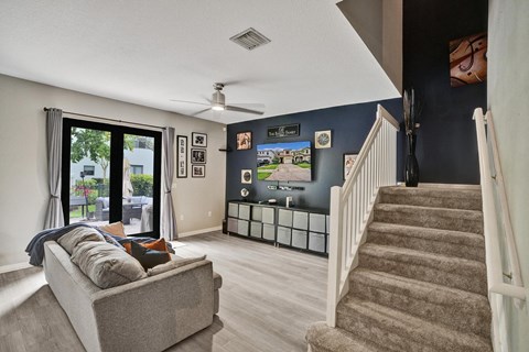 A living room with a grey couch and a staircase.