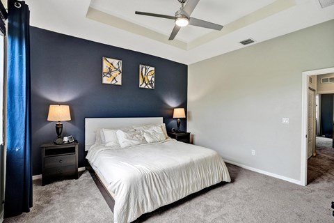 A bedroom with a bed, two nightstands with lamps, and a ceiling fan.