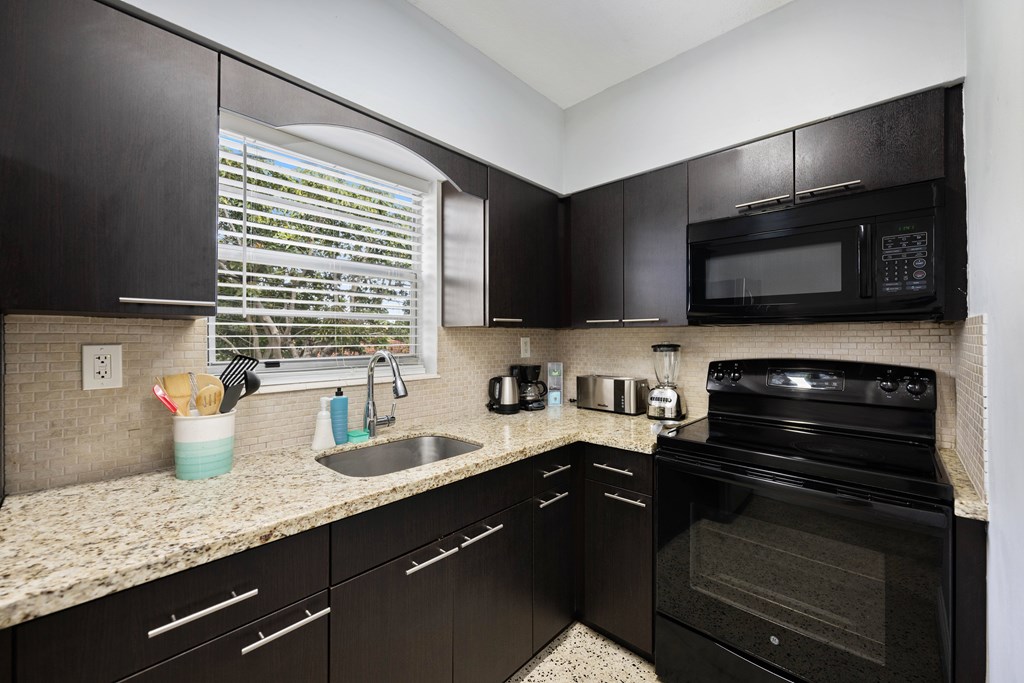 A kitchen with black cabinets and appliances.