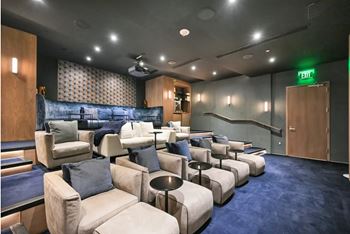 A room with a blue carpet and a row of white couches.