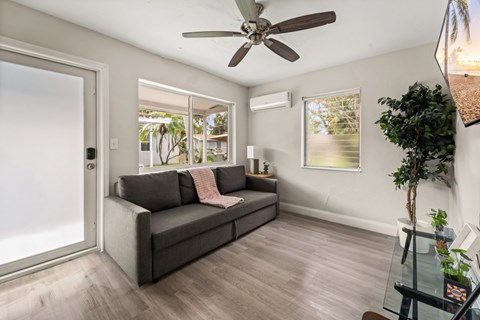 A living room with a grey couch and a ceiling fan.