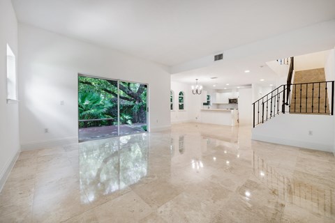 A spacious room with marble flooring and a staircase on the right side.