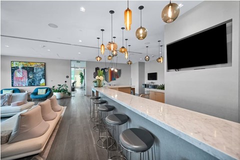 A modern kitchen with a bar area and a television mounted on the wall.