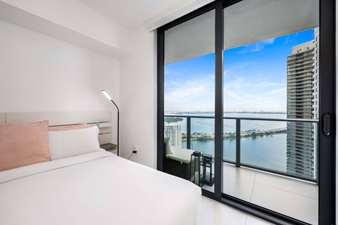 A bedroom with a large bed and a view of the city.