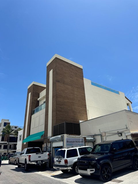A black SUV is parked in front of a building with a white truck and a white van.
