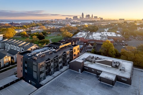 A cityscape is visible in the distance behind a parking lot and buildings.
