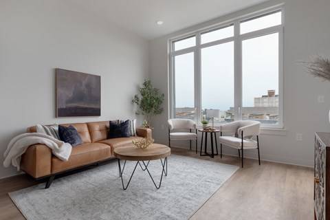 A living room with a brown leather couch, a coffee table, and a painting on the wall.