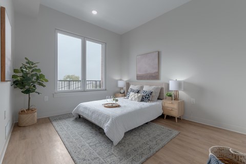 A bedroom with a large bed and a window overlooking a balcony.