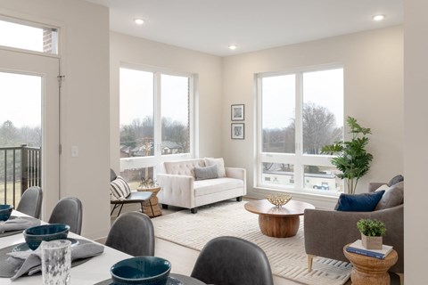 A well-lit living room with a dining table set for two.