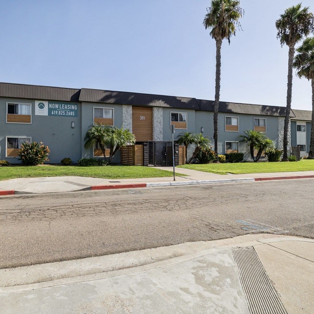 A street view of a Now Leasing sign in front of a building.