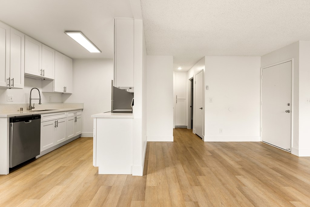 A kitchen with white cabinets and a wooden floor.