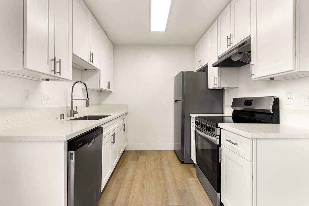 A modern kitchen with white cabinets and black appliances.