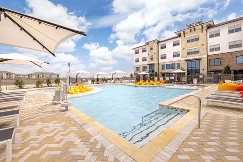A large outdoor swimming pool with sun loungers and umbrellas.