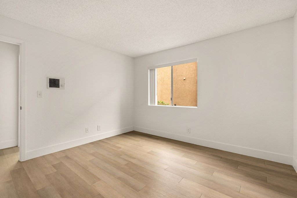 A room with a wooden floor and a window with a wooden shade.