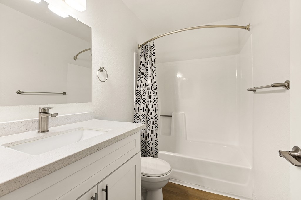 A white bathroom with a toilet, sink, and shower.
