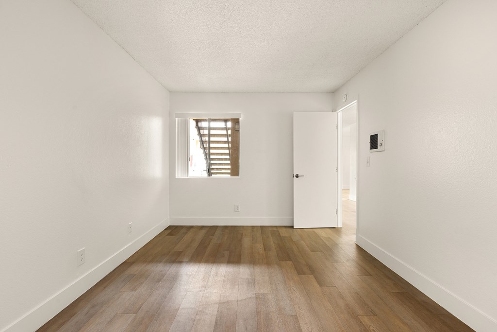 A room with wooden flooring and a window with blinds.