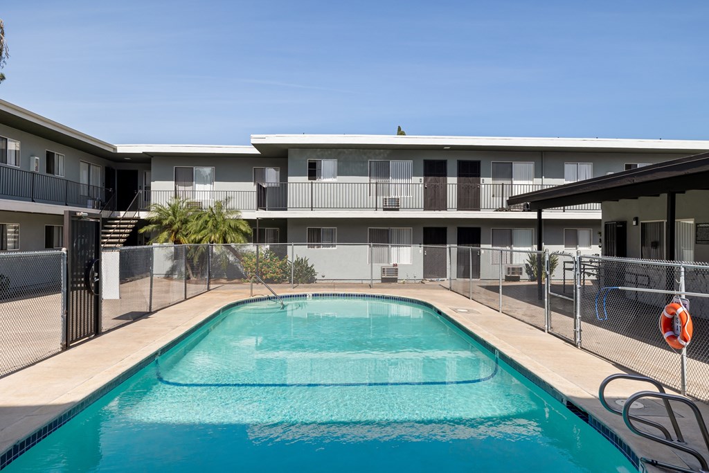 A swimming pool in front of a building with a fence around it.