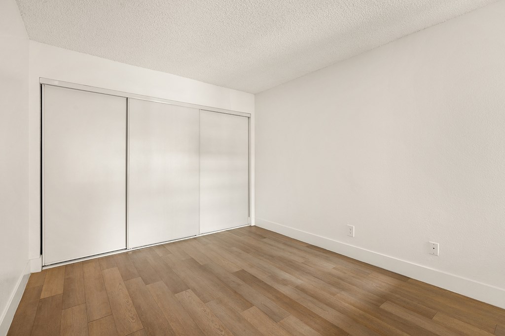 A room with a white wall and a wooden floor.