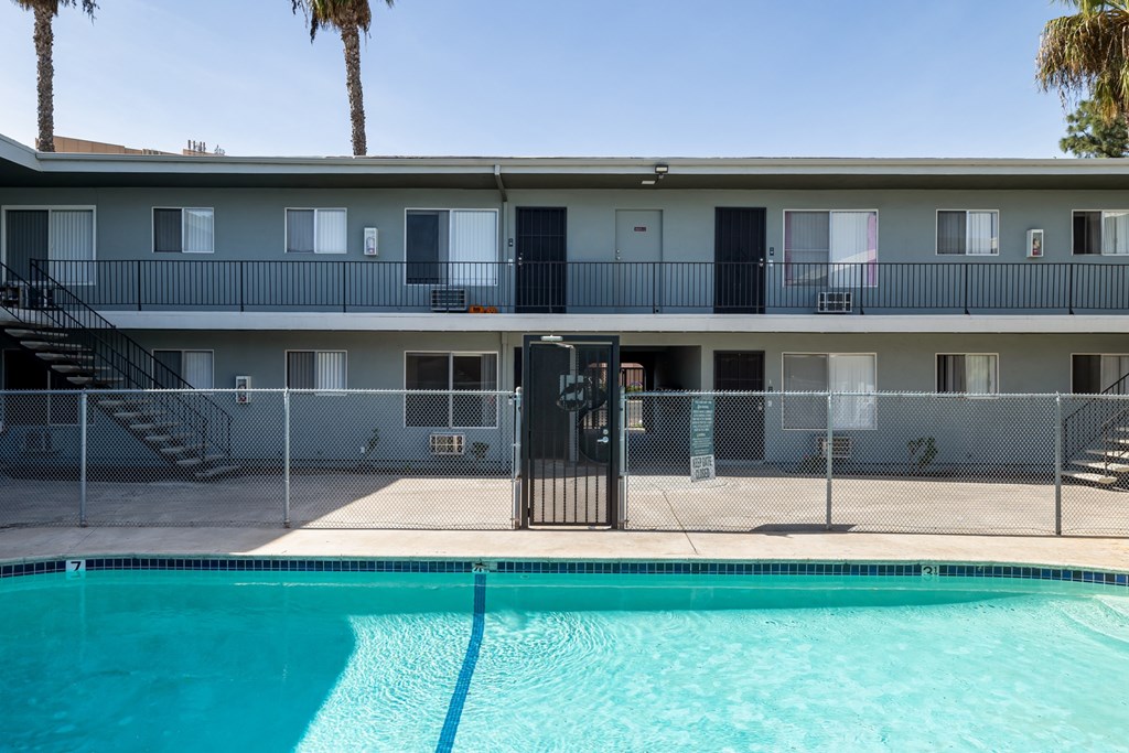 A pool in front of a building with a black gate.