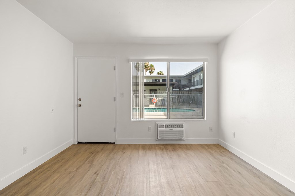 A room with a white door and a window with a view of a building.