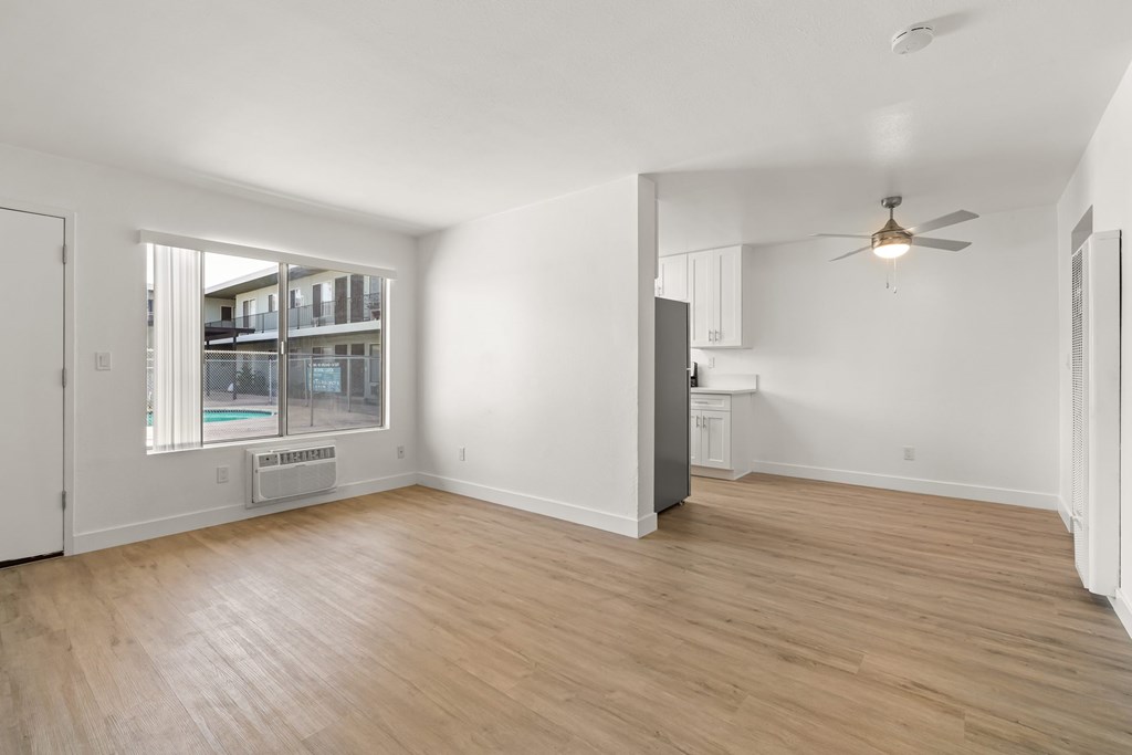 A room with a ceiling fan and a refrigerator.