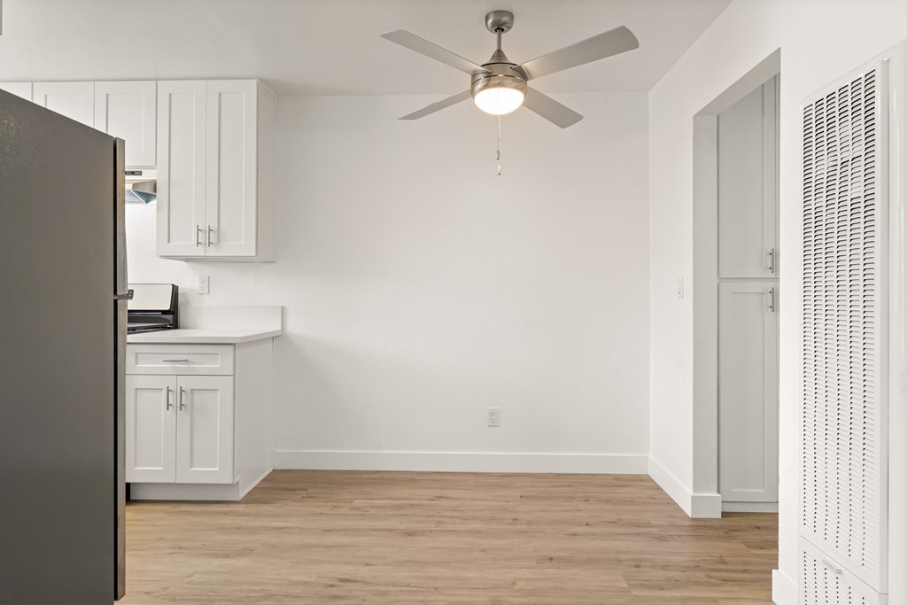 A room with a ceiling fan and a refrigerator.
