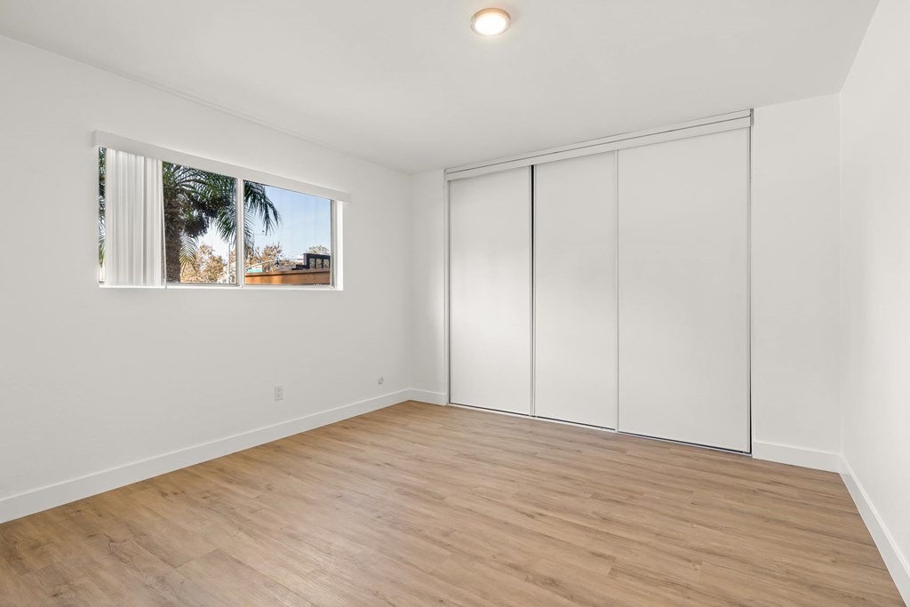 A room with a sliding door and a window with a view of a building and trees outside.