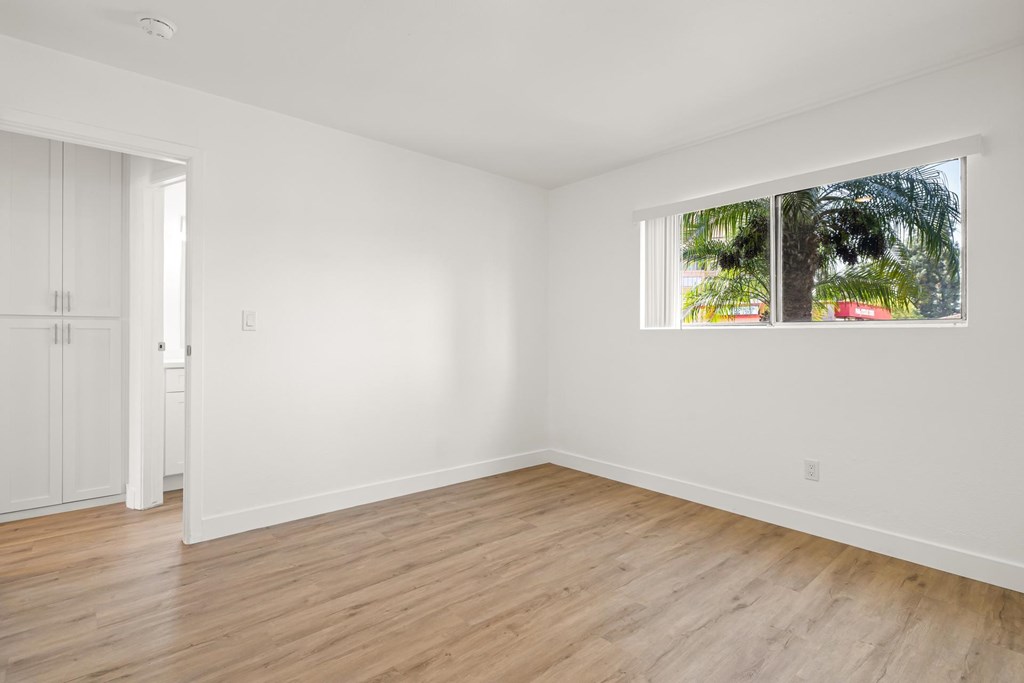 A room with a window and a wooden floor.