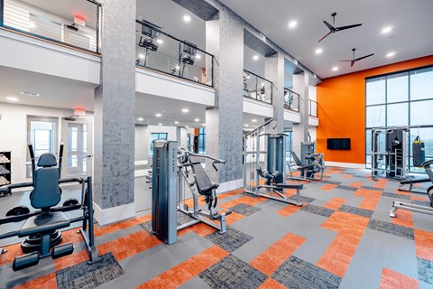 A gym with orange walls and a variety of equipment.