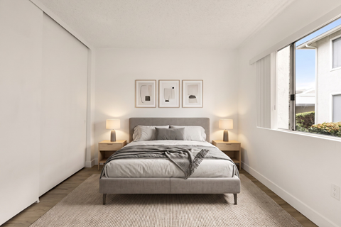 A bedroom with a bed, nightstands, and a window.