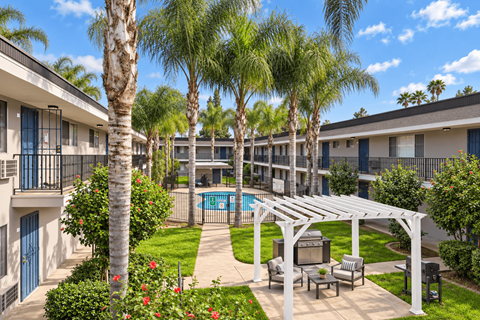 A pool surrounded by palm trees and a white pergola.