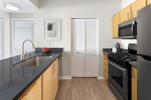 A kitchen with wooden cabinets and black countertops.