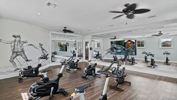 A room full of exercise bikes and a fan on the ceiling.