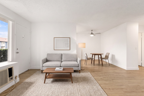 A living room with a grey couch, a brown coffee table, and a painting on the wall.