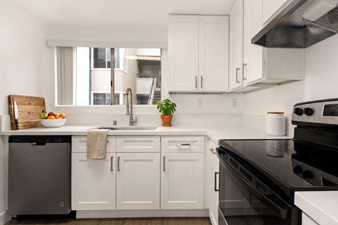 A modern kitchen with white cabinets and black appliances.