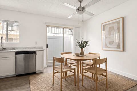 A dining room with a table set for two and a plant on the table.