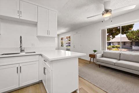 A white kitchen with a couch in the living room.