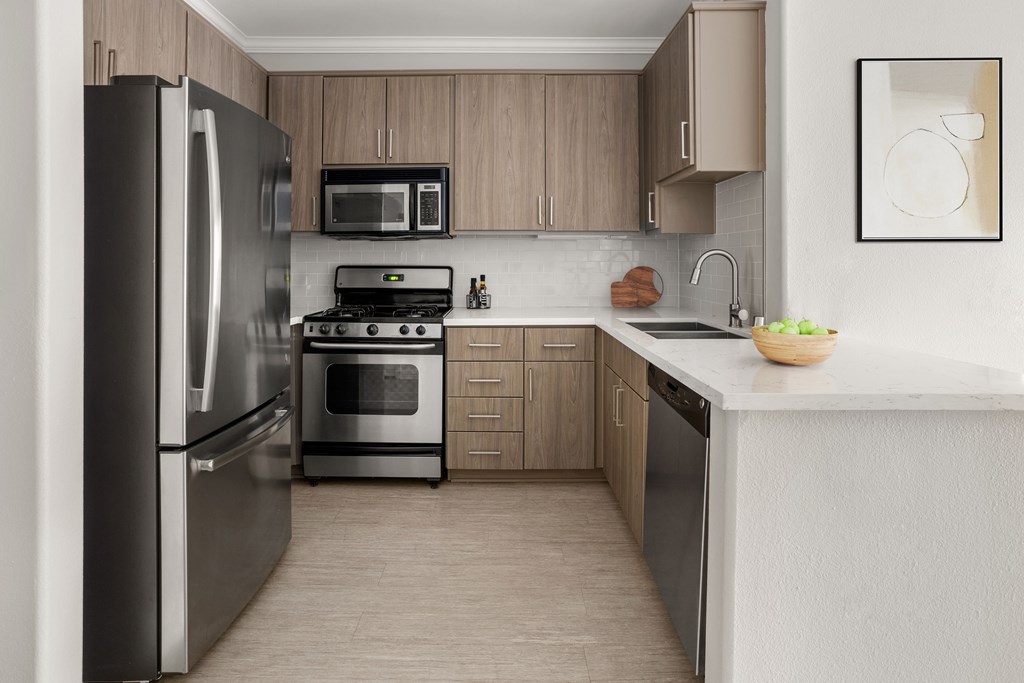 A modern kitchen with a refrigerator, oven, microwave, and sink.