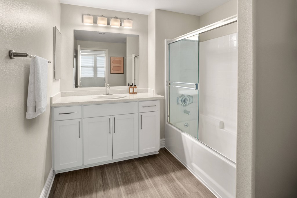 A bathroom with a white cabinet and a glass shower door.