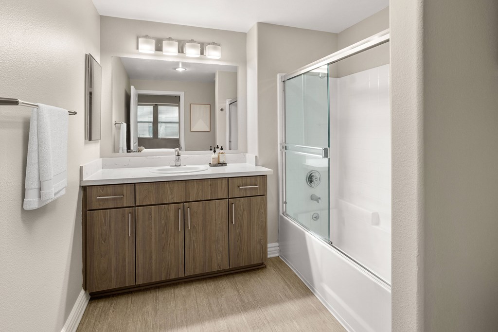 A bathroom with a sink, mirror, and shower.