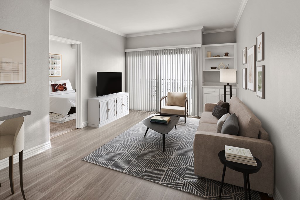 A living room with a grey sofa, a black chair, a grey rug, a white cabinet, a television, and a window with curtains.