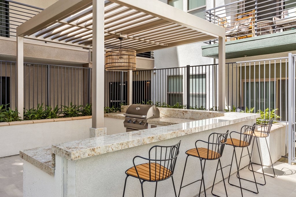A patio with a bar and chairs under a wooden roof.
