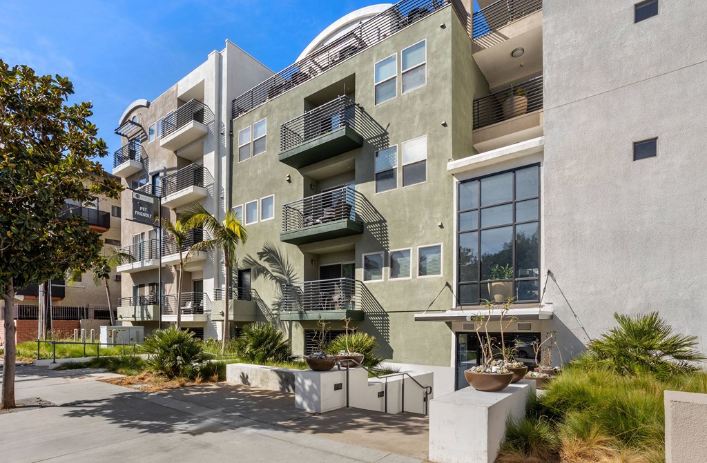 A modern building with a balcony and a tree in front.